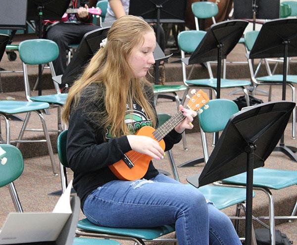 Student playing a ukulele.
